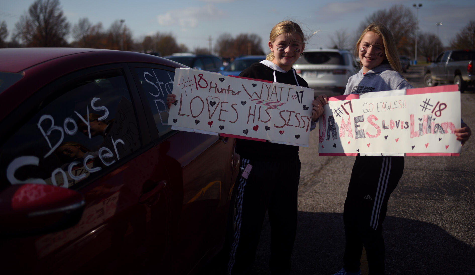 Haleigh Perrsinger, 11, and Lillian Brooks, 12, pose with signs that they made for their brothers